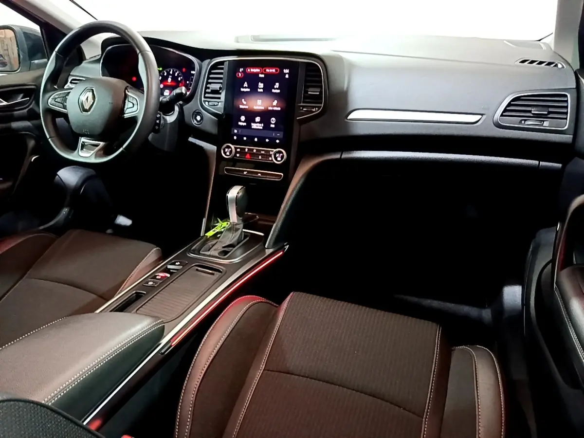 Vue intérieure avant droite de la Renault Mégane Techno TCe 140 2023, avec écran tactile central et éclairage d’ambiance rouge.