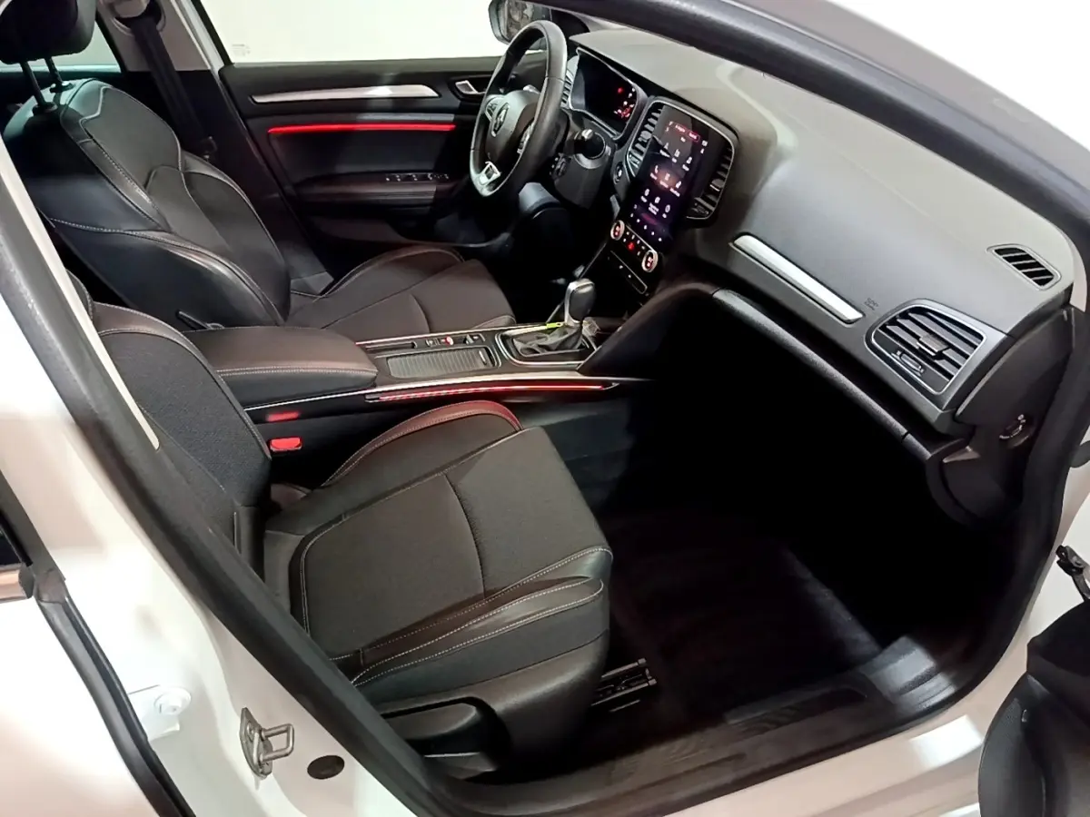 Intérieur avant droit de la Renault Mégane Techno TCe 140 blanc, sièges noirs et éclairage d’ambiance rouge.