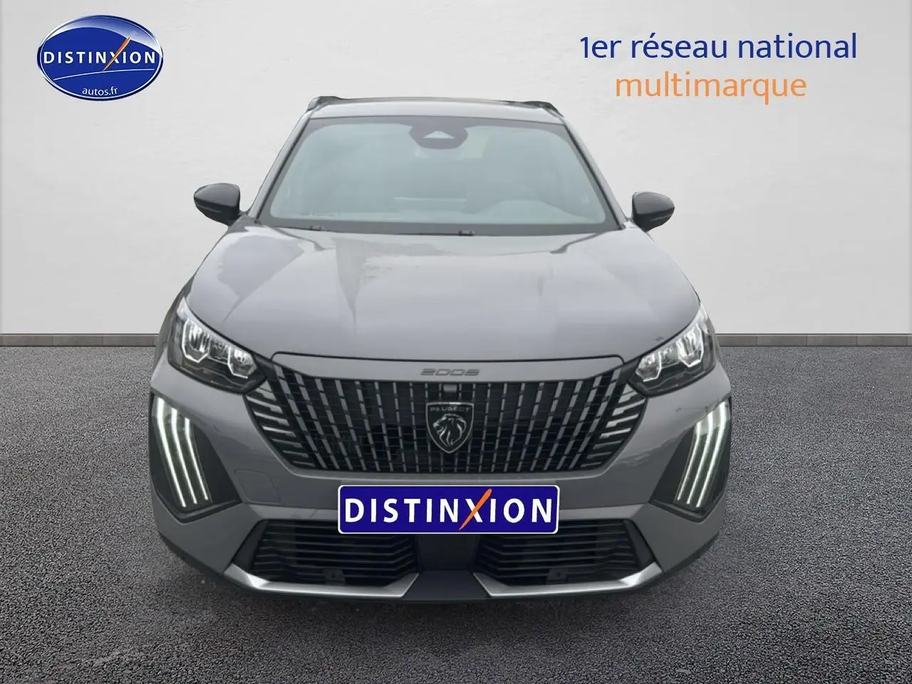 Vue frontale d'un Peugeot 2008 gris sélénite avec calandre noire et feux LED verticaux allumés.