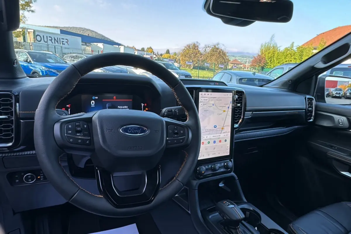 Intérieur du Ford Ranger PHEV 281 Wildtrak 2025 vu depuis le siège conducteur, tableau de bord noir avec écran tactile vertical.