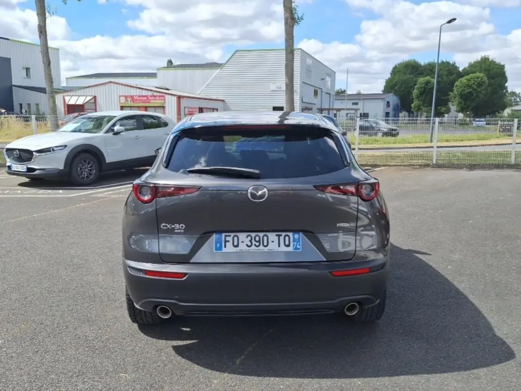 Vue arrière d'un Mazda CX-30 gris 2020 avec vitres surteintées et double sortie d'échappement visible.