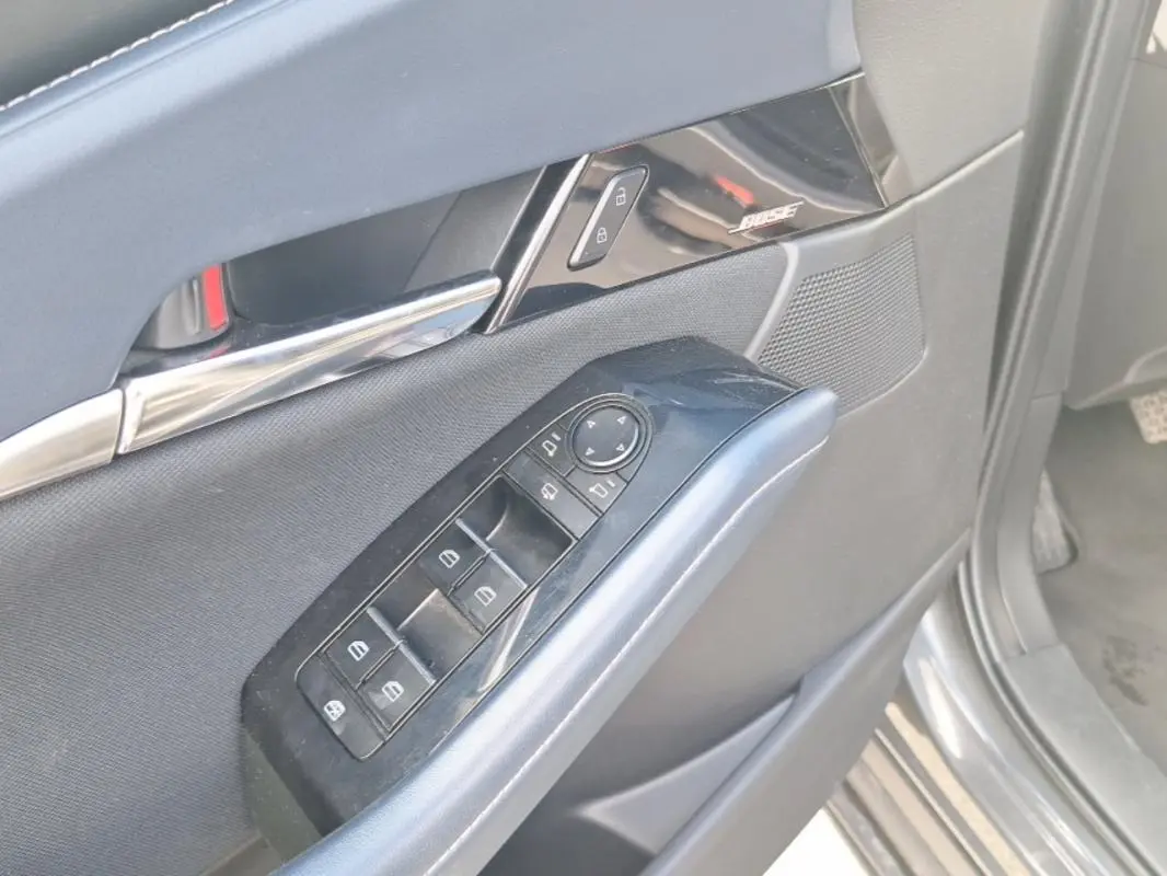 Gros plan sur la porte côté conducteur de la Mazda CX-30 gris, montrant les commandes des vitres et le haut-parleur Bose intégré.