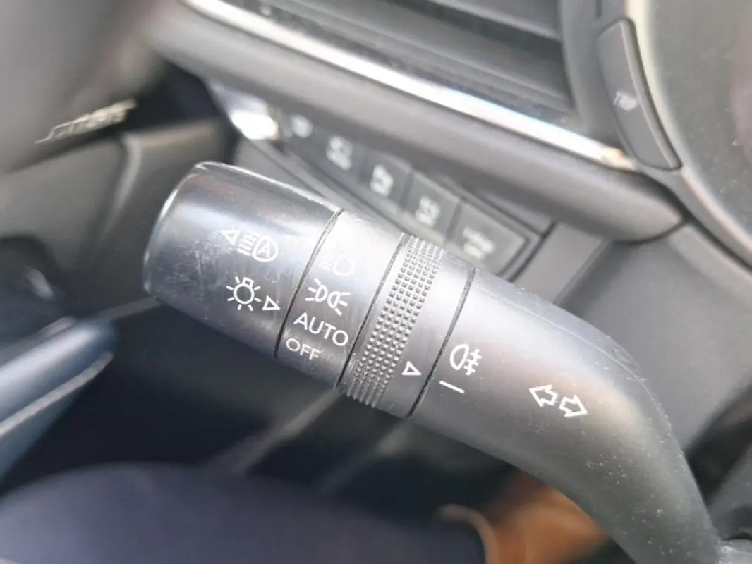 Gros plan sur la commande des feux et clignotants noire à l'intérieur du Mazda CX-30 gris, version 2020.