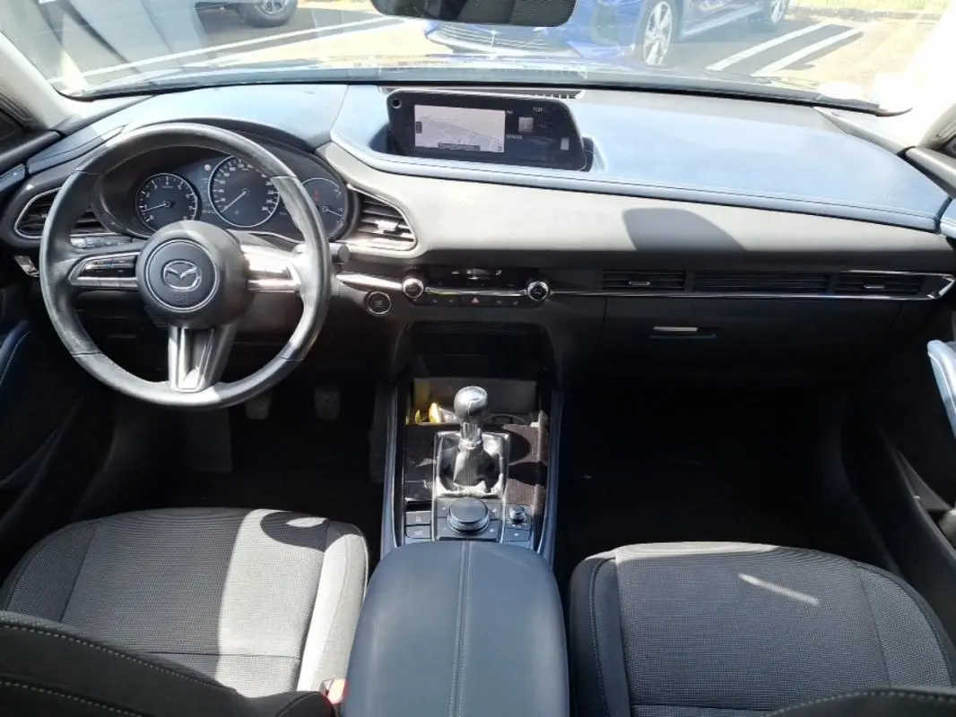 Vue intérieure avant du Mazda CX-30 2020, tableau de bord noir avec écran GPS et levier de vitesse manuel.