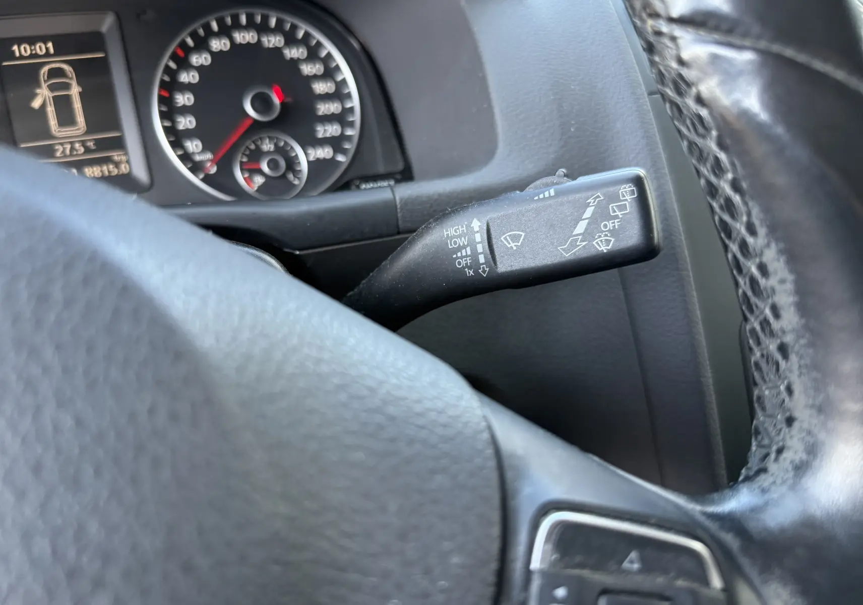 Vue rapprochée du commodo d’essuie-glace à droite du volant noir dans le tableau de bord d’un Volkswagen Touran gris 2012.