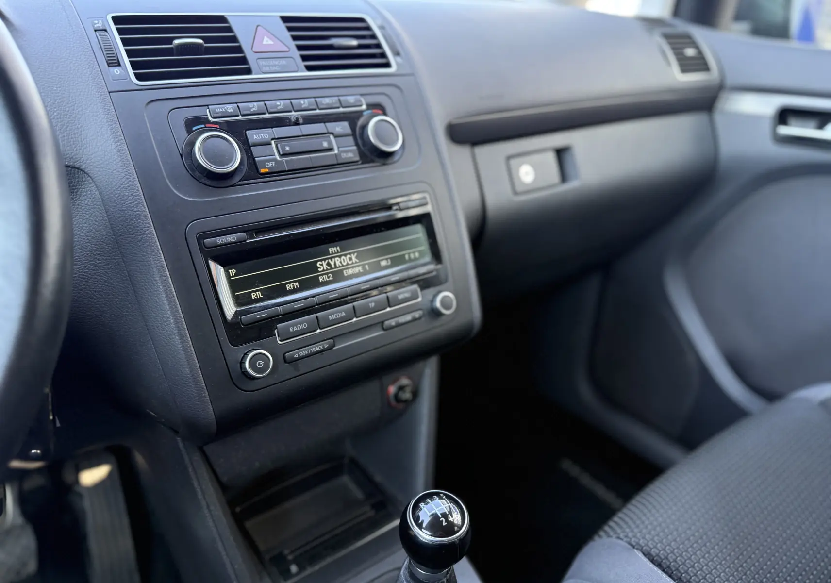 Vue intérieure côté passager du tableau de bord gris et levier de vitesse manuel d’un Volkswagen Touran 1.4 TSI 7 places de 2012.