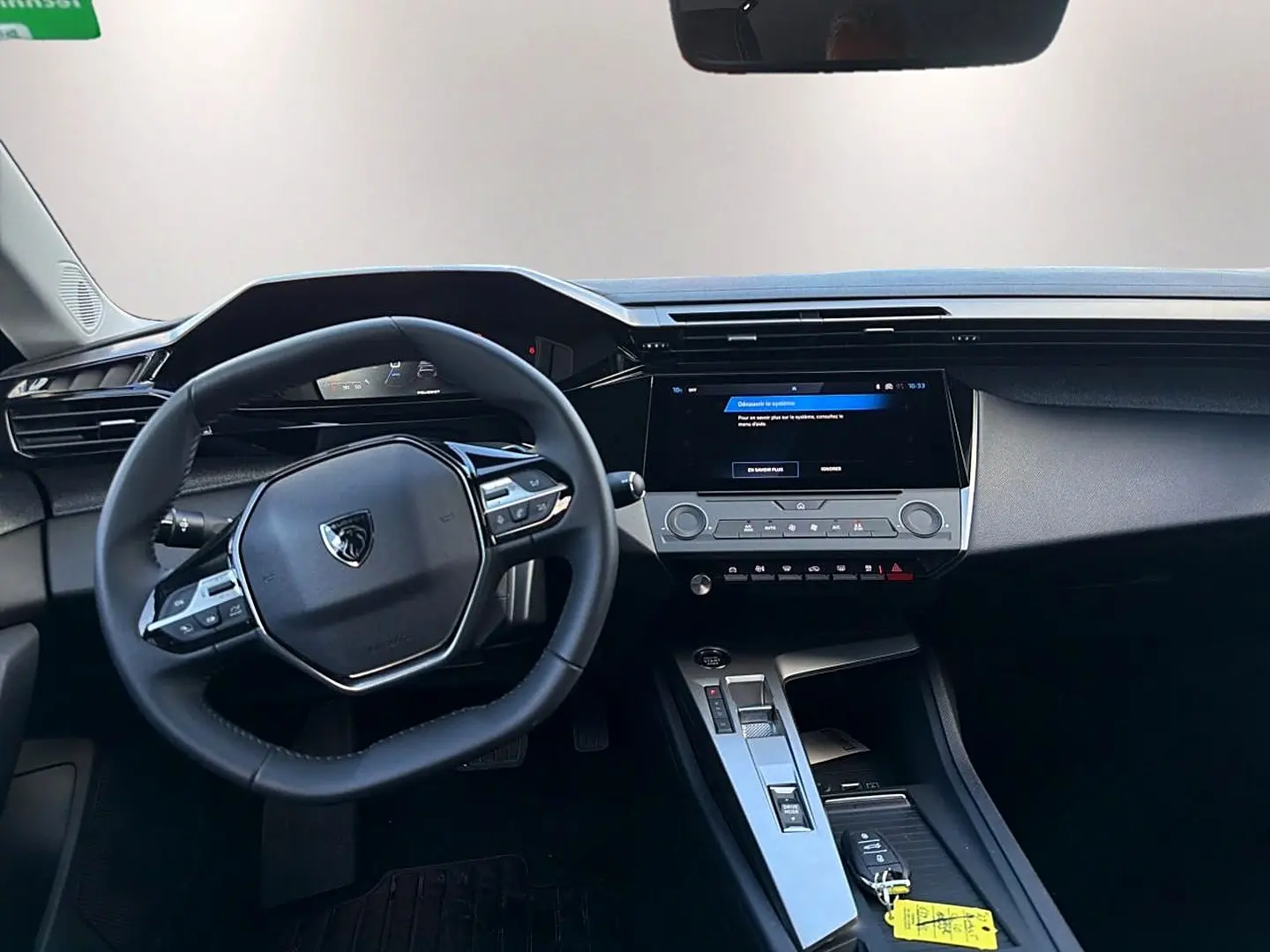 Vue intérieure du poste de conduite de la Peugeot 308 gris selenium, avec volant multifonction et écran tactile central.