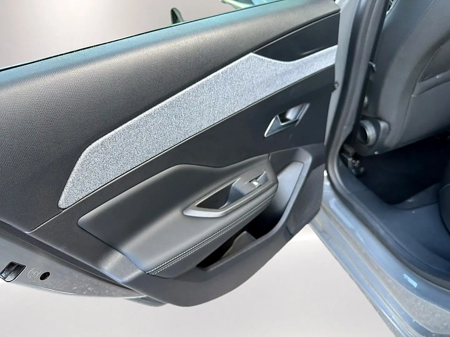 Vue rapprochée de la porte arrière gauche grise selenium de la Peugeot 308 2025 avec habillage tissu clair et commandes de vitre.
