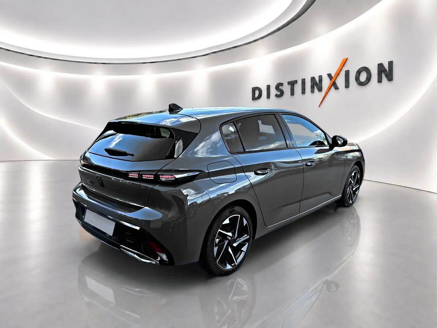 Peugeot 308 gris selenium vue 3/4 arrière droit dans un showroom lumineux avec jantes alu noires et chrome.