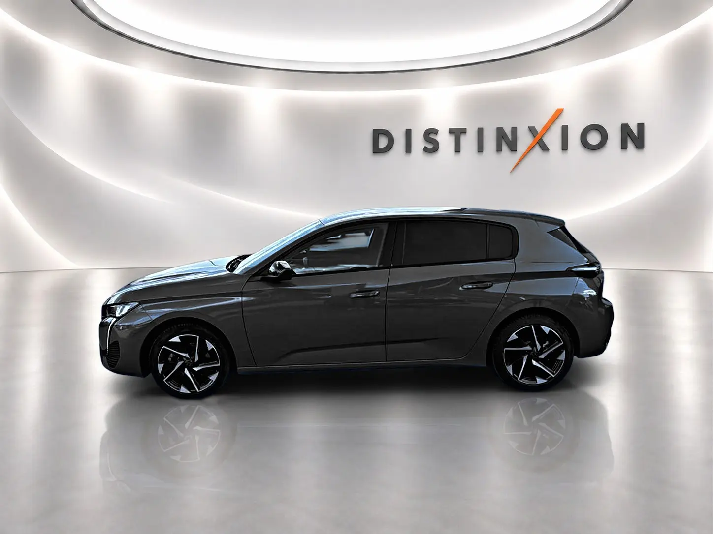 Profil droit d'une Peugeot 308 gris selenium 2025 dans un showroom lumineux avec jantes alu noires et logo Distinxion en arrière-plan.