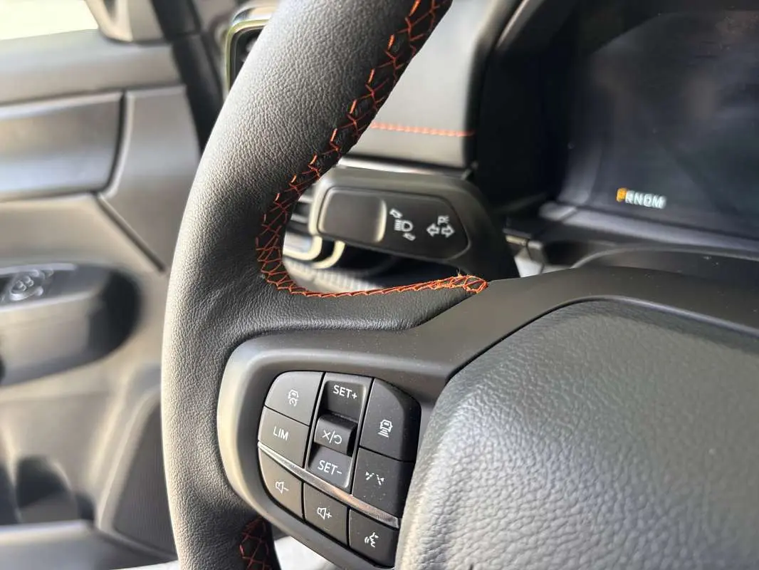 Gros plan sur le volant cuir noir avec surpiqûres rouges du Ford Ranger Wildtrak Plus 2026, côté gauche.