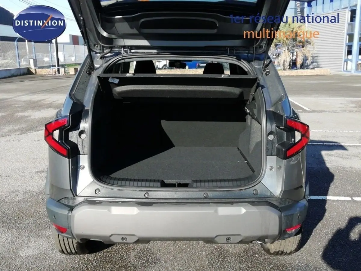 Vue arrière du Dacia Duster gris schiste métal 2026 avec coffre ouvert et feux arrière LED visibles.