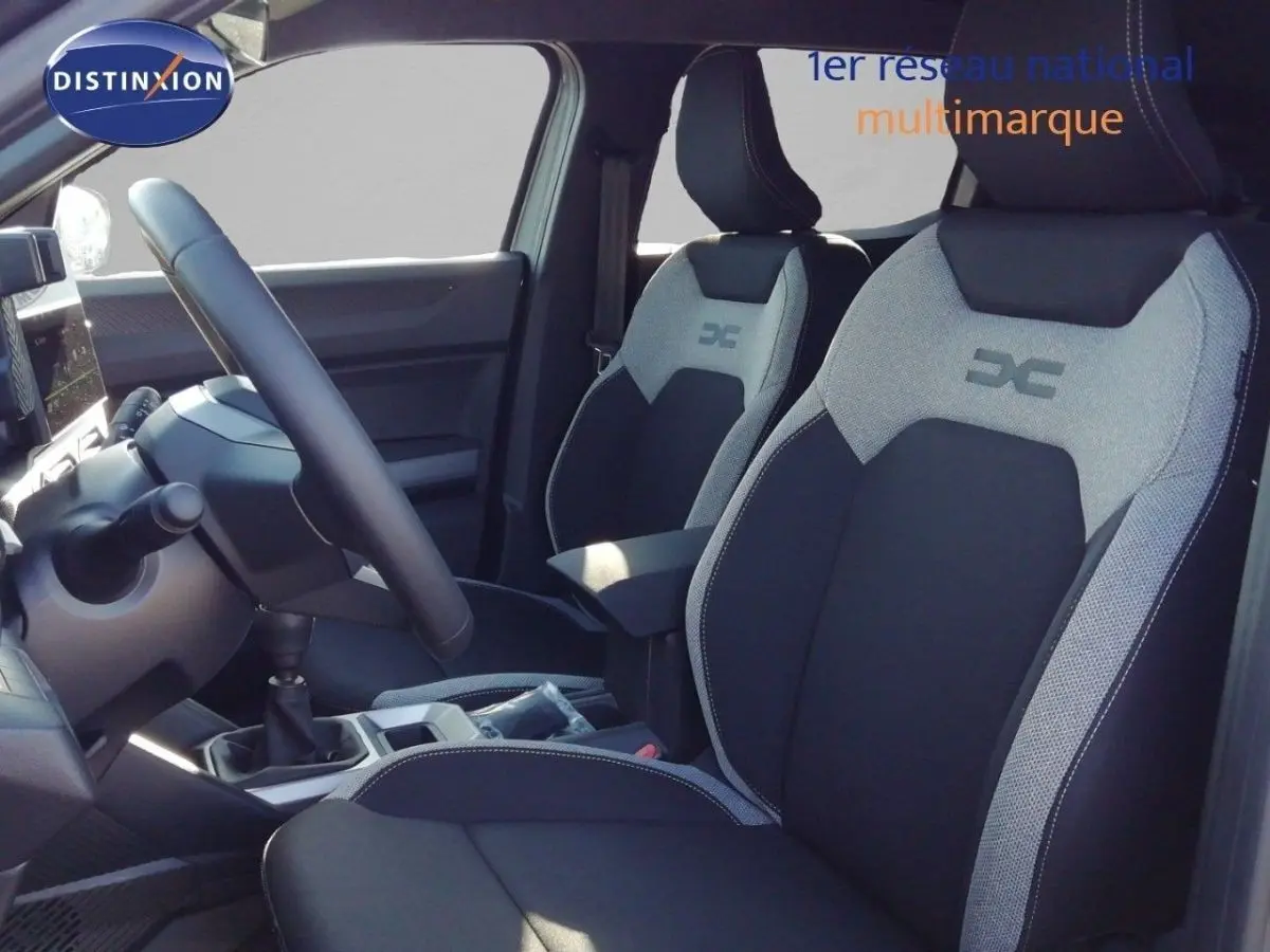 Vue intérieure côté conducteur du Dacia Duster TCE MHEV 140ch Journey 2026, sièges bi-ton noir et gris avec logo DC.