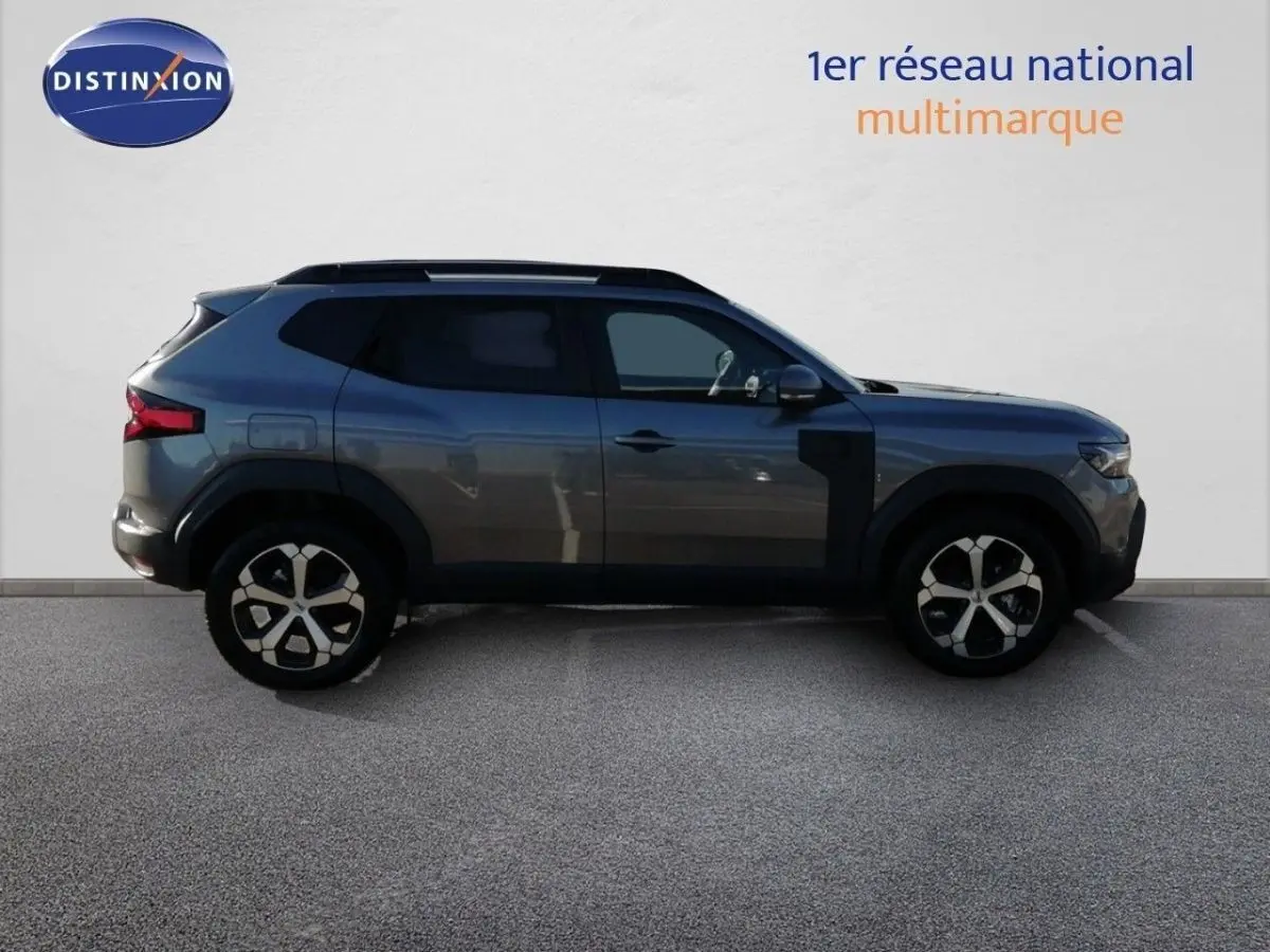 Profil latéral droit du Dacia Duster TCE MHEV gris schiste métal, soulignant ses jantes bi-ton et ses lignes robustes.