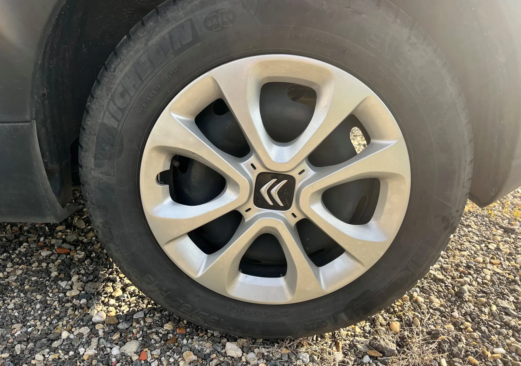 Gros plan sur la roue avant gauche d'une Citroën C3 blanche de 2019, mettant en valeur la jante aluminium et le logo Citroën.