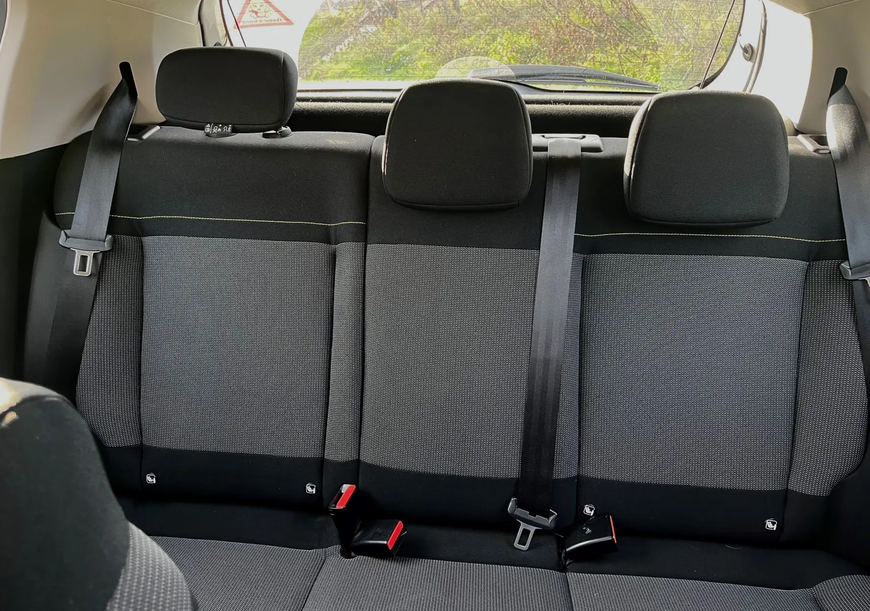 Vue intérieure arrière des sièges noirs et gris de la Citroën C3 blanche 2019, avec ceintures de sécurité visibles.