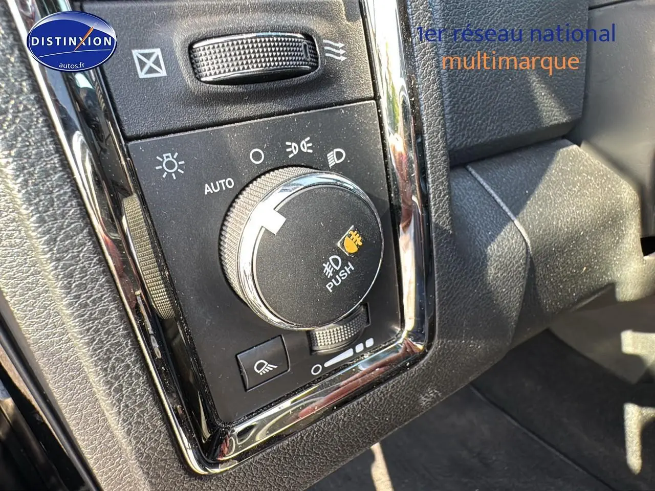 Gros plan sur le bouton de commande des phares du Dodge RAM 5.7 V8 noir, intérieur avec finitions chromées.
