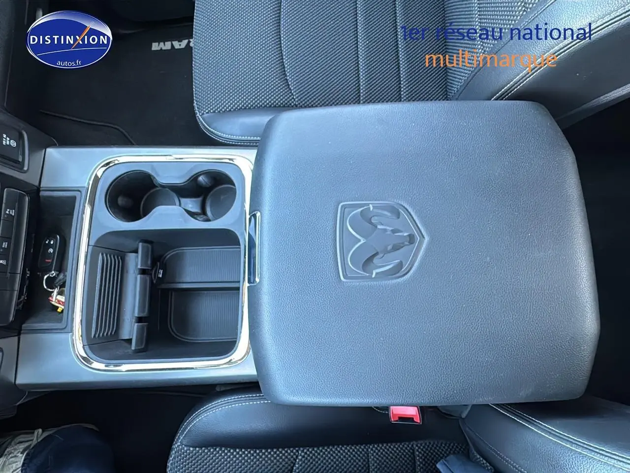 Vue plongeante sur la console centrale noire du Dodge RAM 5.7 V8 Crew Sport 2020 avec porte-gobelets et logo RAM embossé.
