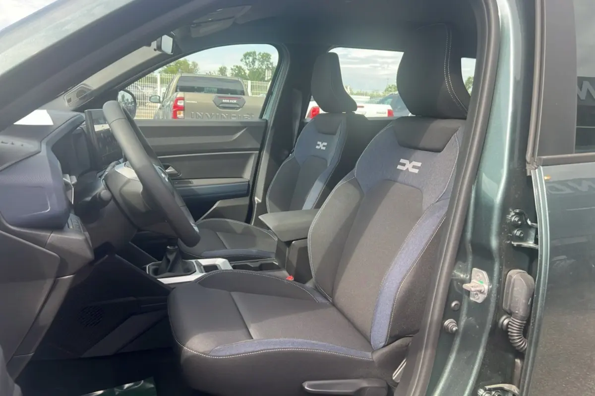 Vue intérieure côté conducteur du Dacia Bigster vert cèdre, mettant en valeur les sièges tissu bi-color avec logo brodé.