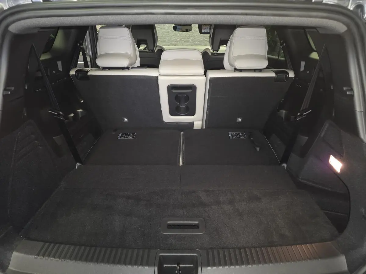 Coffre ouvert vu de l'arrière du Renault Espace gris, avec banquette arrière partiellement rabattue et sellerie claire.