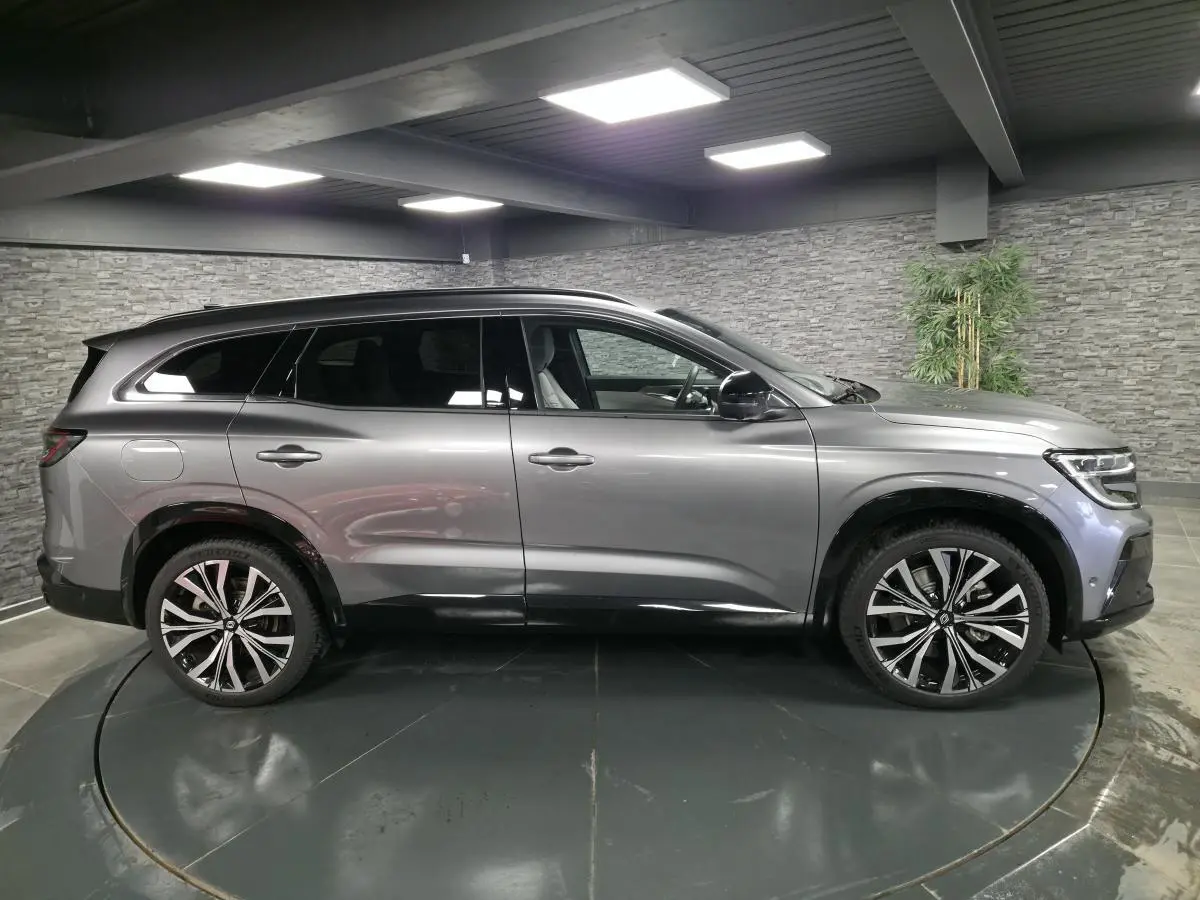 Profil droit du Renault Espace gris Baltique 2025 avec jantes alliage 20 pouces et barres de toit noir matifié.