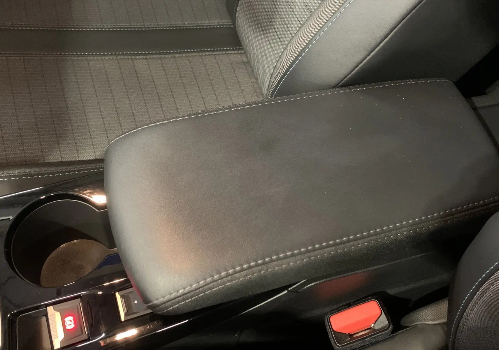 Gros plan sur l'accoudoir central noir et siège tissu gris à motifs dans l'habitacle d'une Peugeot 208 gris 2021.