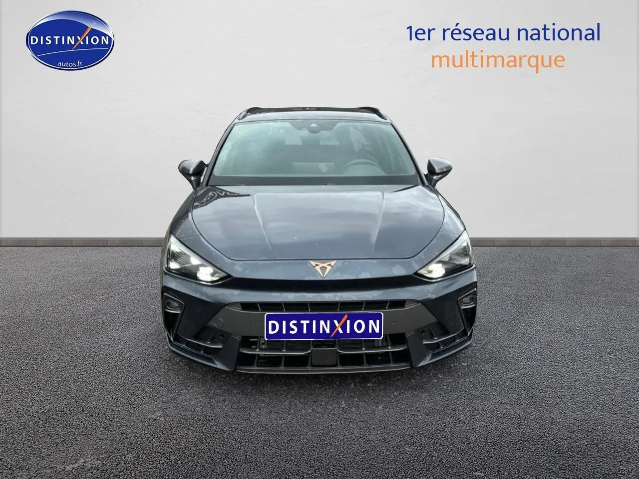 Vue frontale d'une CUPRA Leon ST 1.5 etsi hybrid gris magnétique avec phares LED allumés sur fond neutre.