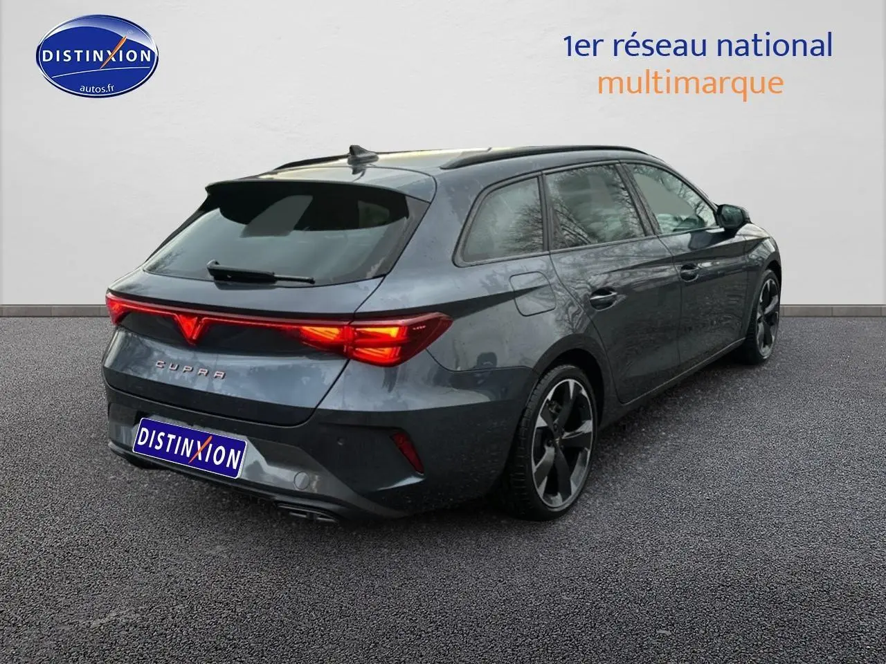 Vue 3/4 arrière droite d'une CUPRA Leon ST gris magnétique avec feux arrière LED allumés sur fond neutre.