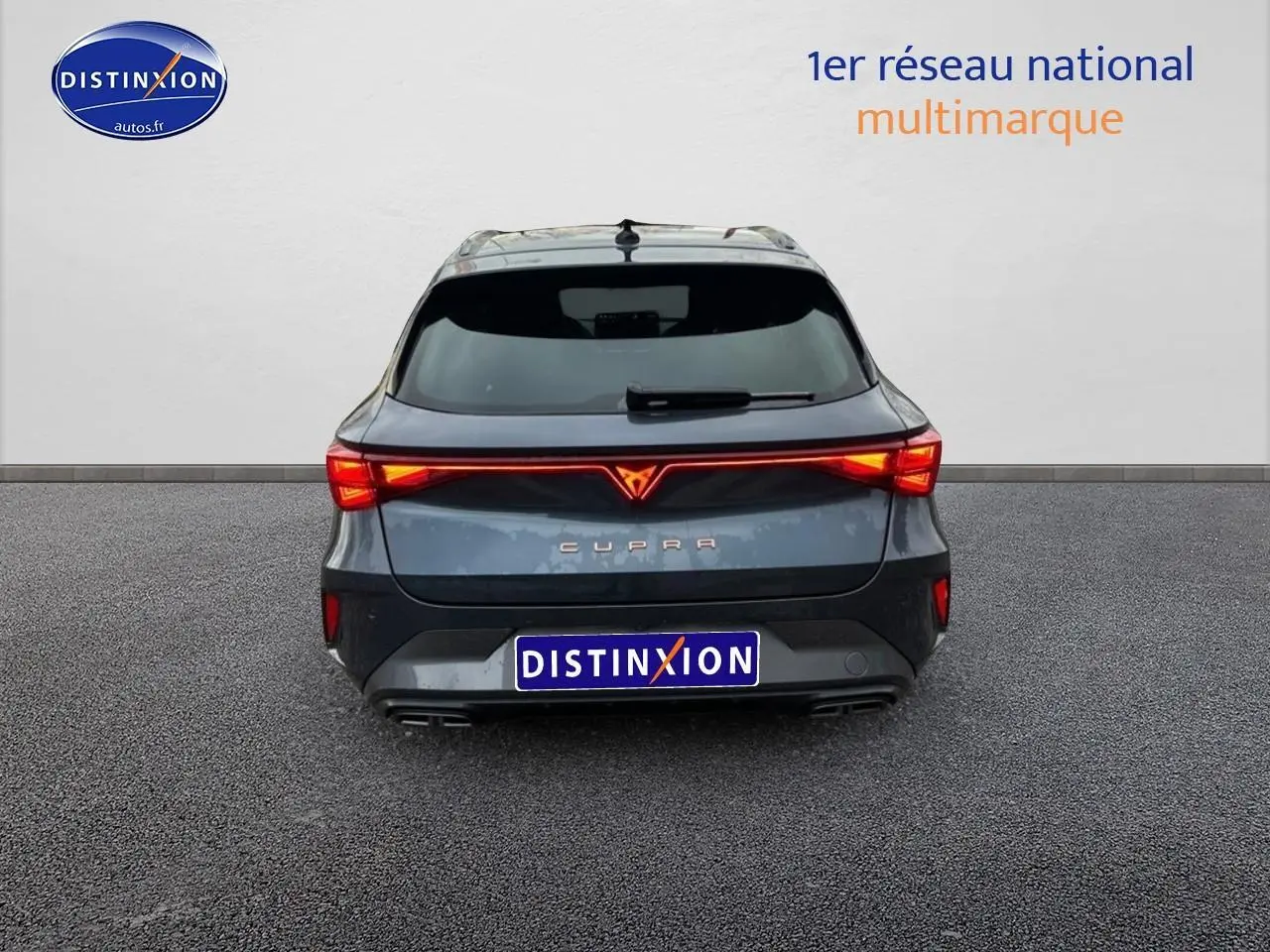 Vue arrière d'une CUPRA Leon ST gris magnétique avec feux LED allumés et double sortie d'échappement visible.