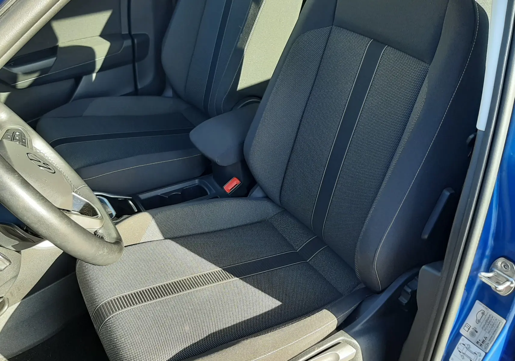 Vue intérieure côté conducteur du Volkswagen T-Roc bleu 2022, sièges tissu gris foncé avec surpiqûres contrastantes.