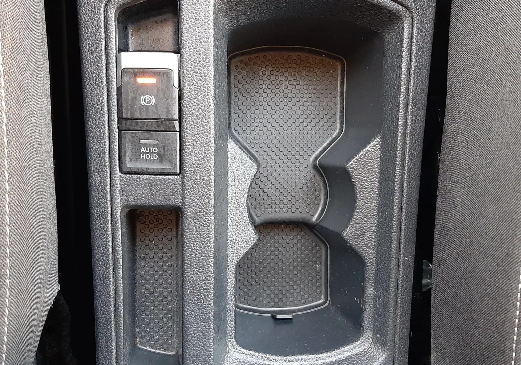 Gros plan sur la console centrale du Volkswagen T-Roc 1.5 TSI 2022, montrant le frein à main électrique et porte-gobelets.