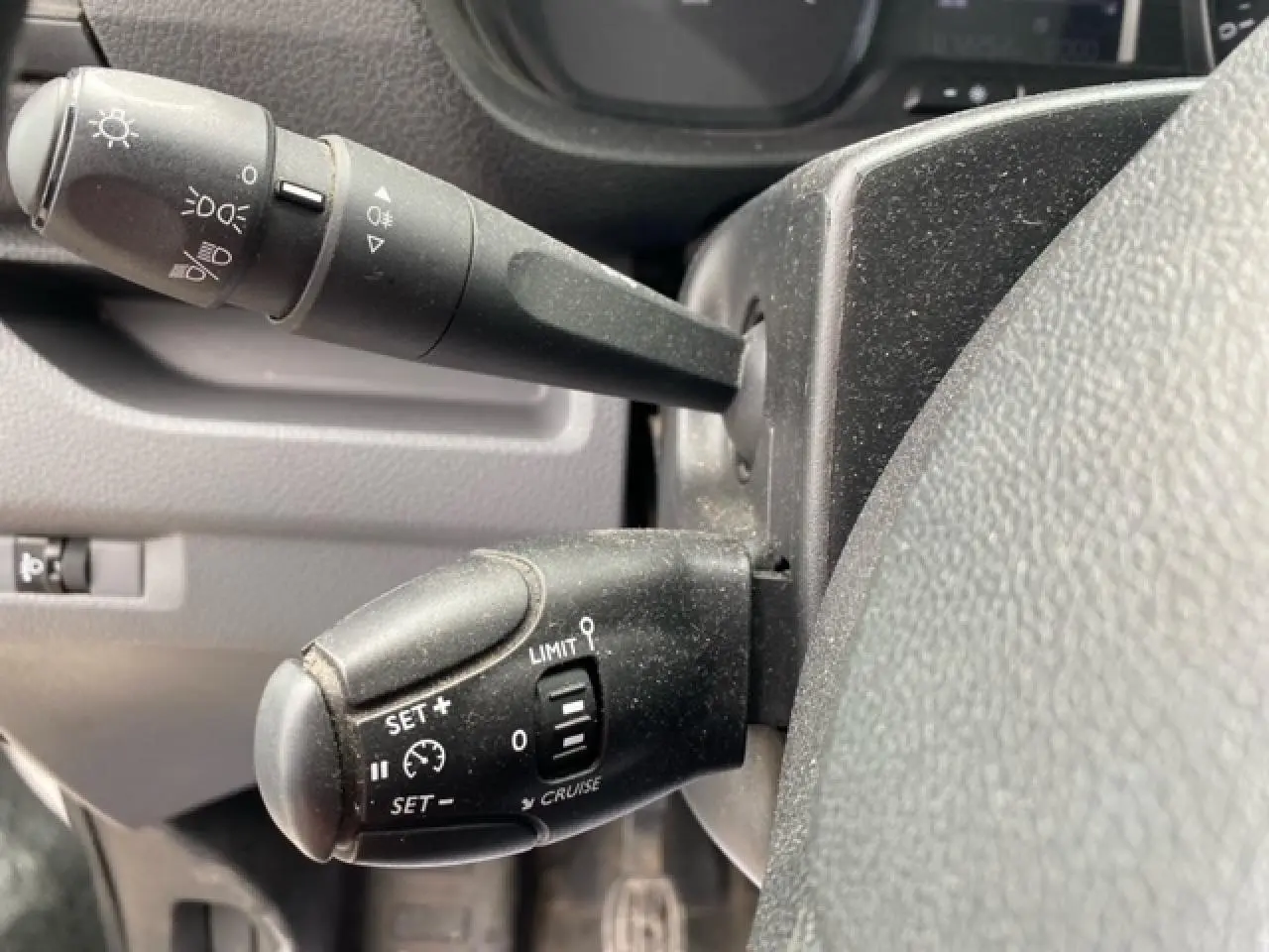 Gros plan sur les commandes au volant du Citroën Jumpy blanc 2019, montrant les leviers de régulateur et de feux.