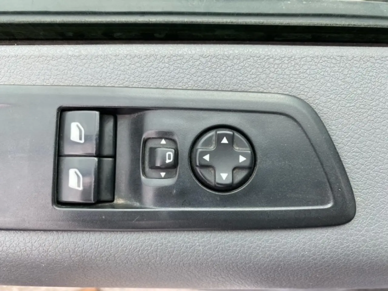Gros plan sur les commandes électriques des vitres et des rétroviseurs sur la porte intérieure d’un Citroën Jumpy blanc.