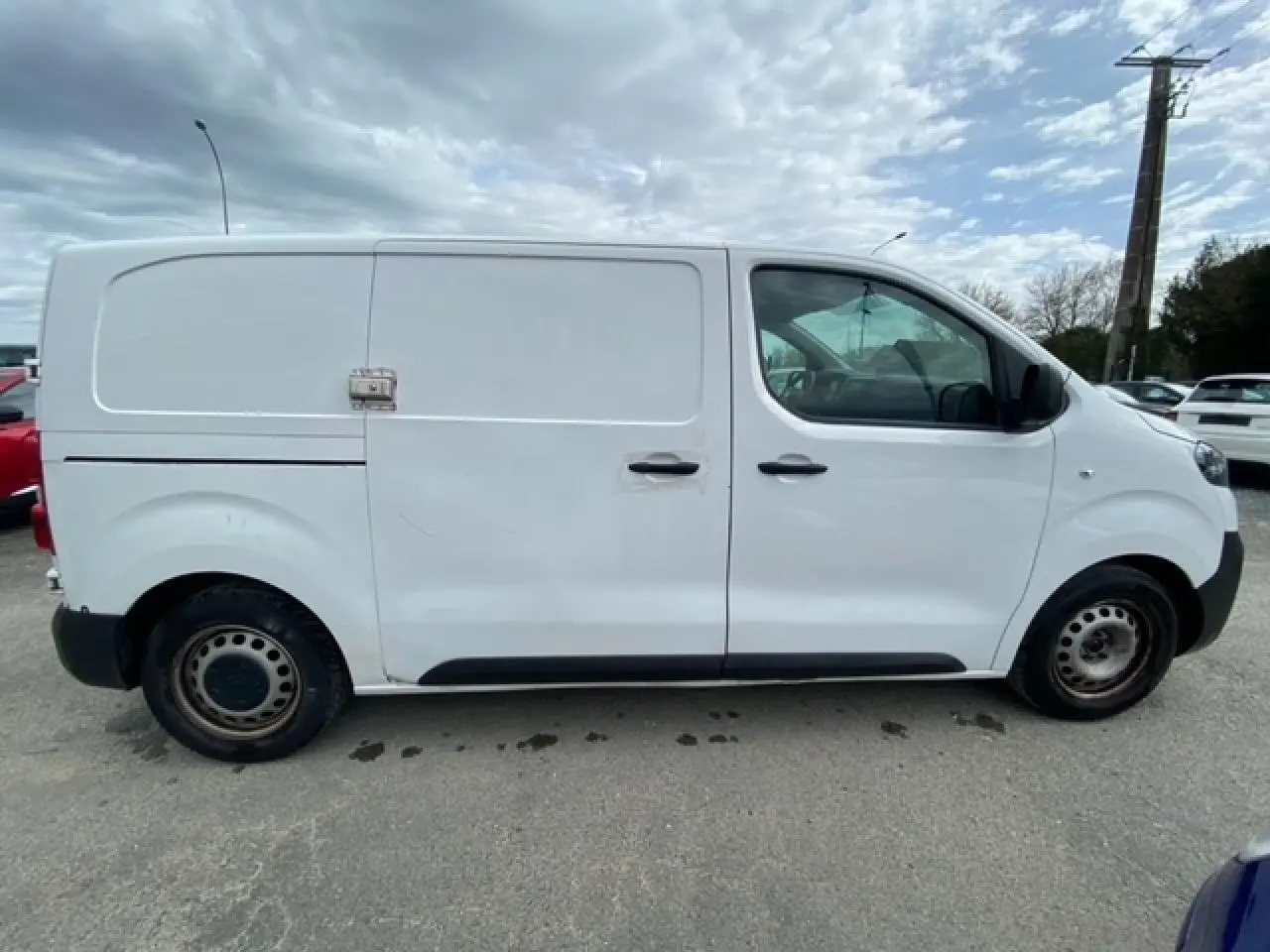 Vue de profil côté droit d’un utilitaire Citroën Jumpy blanc avec porte coulissante et roues acier.