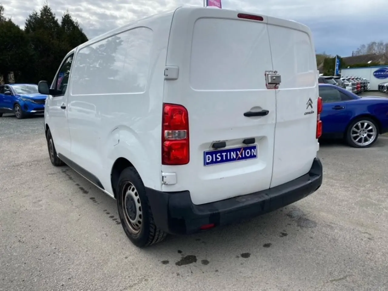 Vue 3/4 arrière droite d’un utilitaire Citroën Jumpy blanc avec portes arrière battantes et pare-chocs noir.