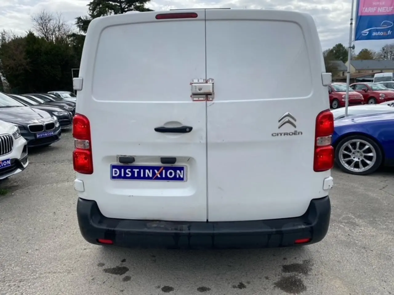 Vue arrière d'un utilitaire Citroën Jumpy blanc avec portes battantes et pare-chocs noir, stationné en extérieur.