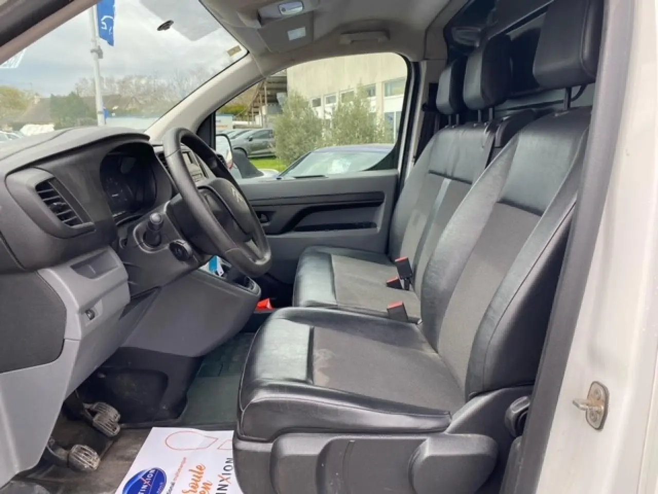 Vue intérieure côté conducteur du Citroën Jumpy blanc 2019, sièges mixtes TEP/tissu noirs et tableau de bord visible.