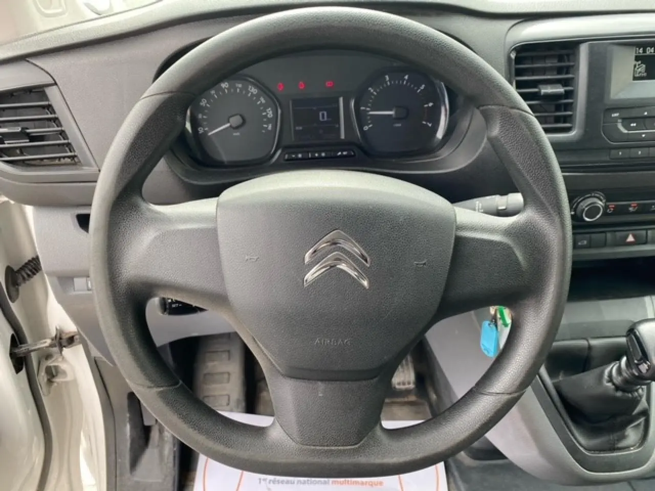 Vue intérieure centrée sur le volant noir du Citroën Jumpy blanc de 2019 avec tableau de bord et levier de vitesses manuelle.