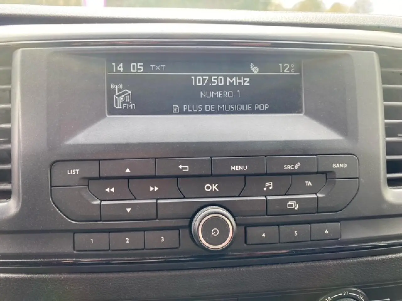 Gros plan sur l’autoradio du Citroën Jumpy blanc 2019 affichant la fréquence FM 107.50 MHz et la température extérieure.