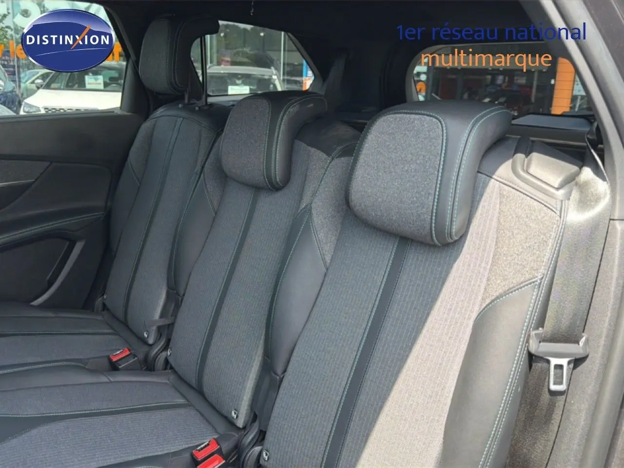Vue intérieure sur les sièges arrière du Peugeot 5008 2023, tissu gris avec surpiqûres bleues et ceintures visibles.