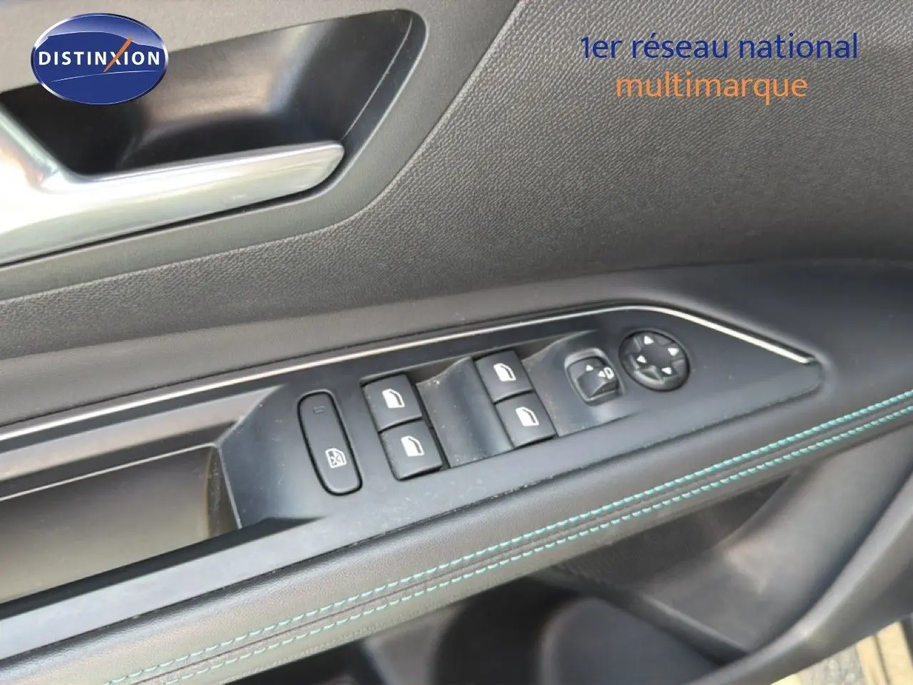 Gros plan sur la commande des vitres côté gauche du Peugeot 5008 2023 gris Platinium avec surpiqûres bleues.