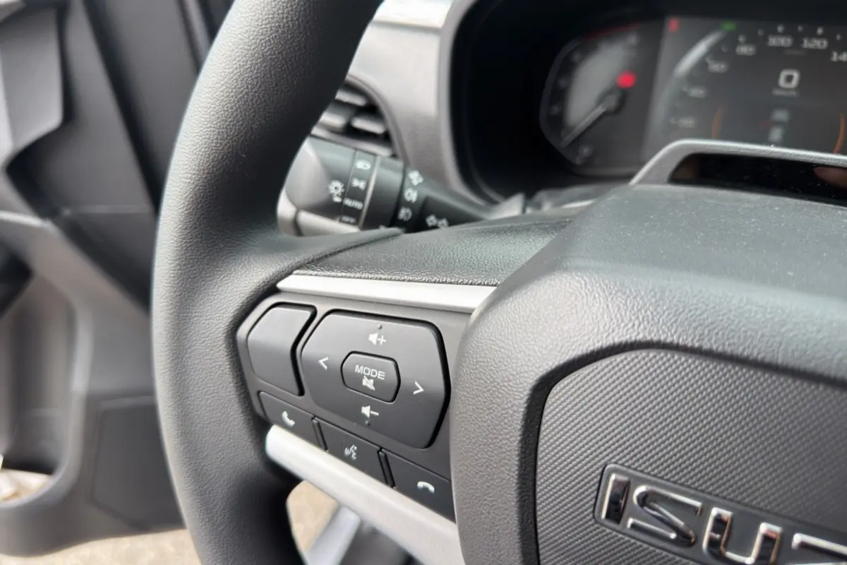Gros plan sur le volant multifonctions noir de l'Isuzu D-MAX 2026, avec commandes audio et téléphone intégrées.