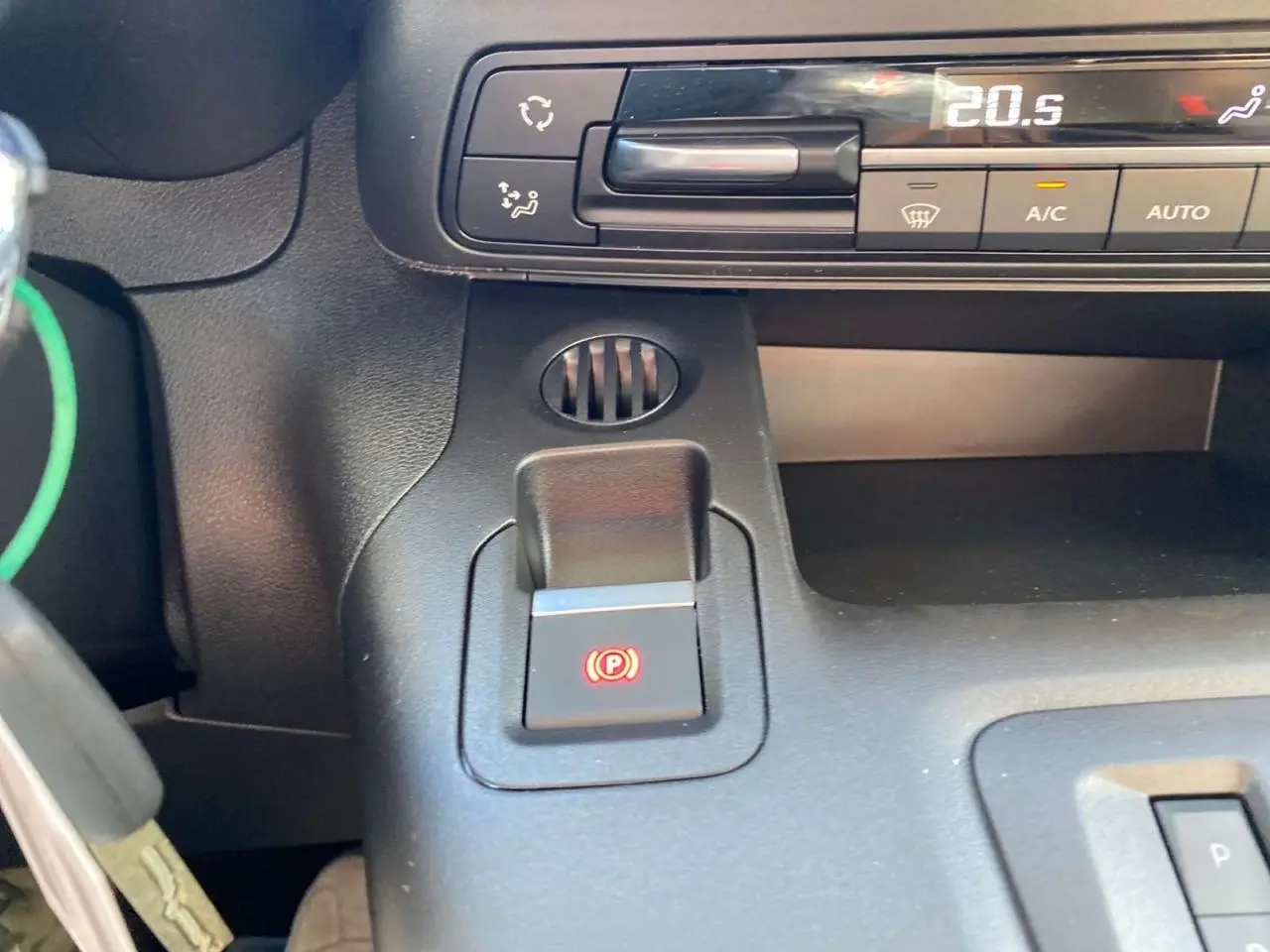 Détail du frein de stationnement électrique et commandes de climatisation du Citroën Berlingo 2026 noir, intérieur avant.