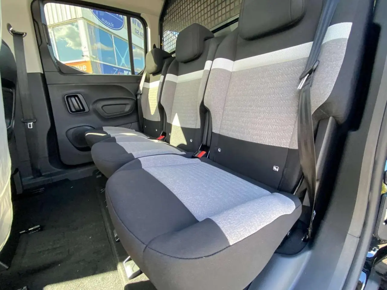 Vue intérieure côté droit des sièges arrière gris et noirs du Citroën Berlingo noir, avec séparation grillagée visible.