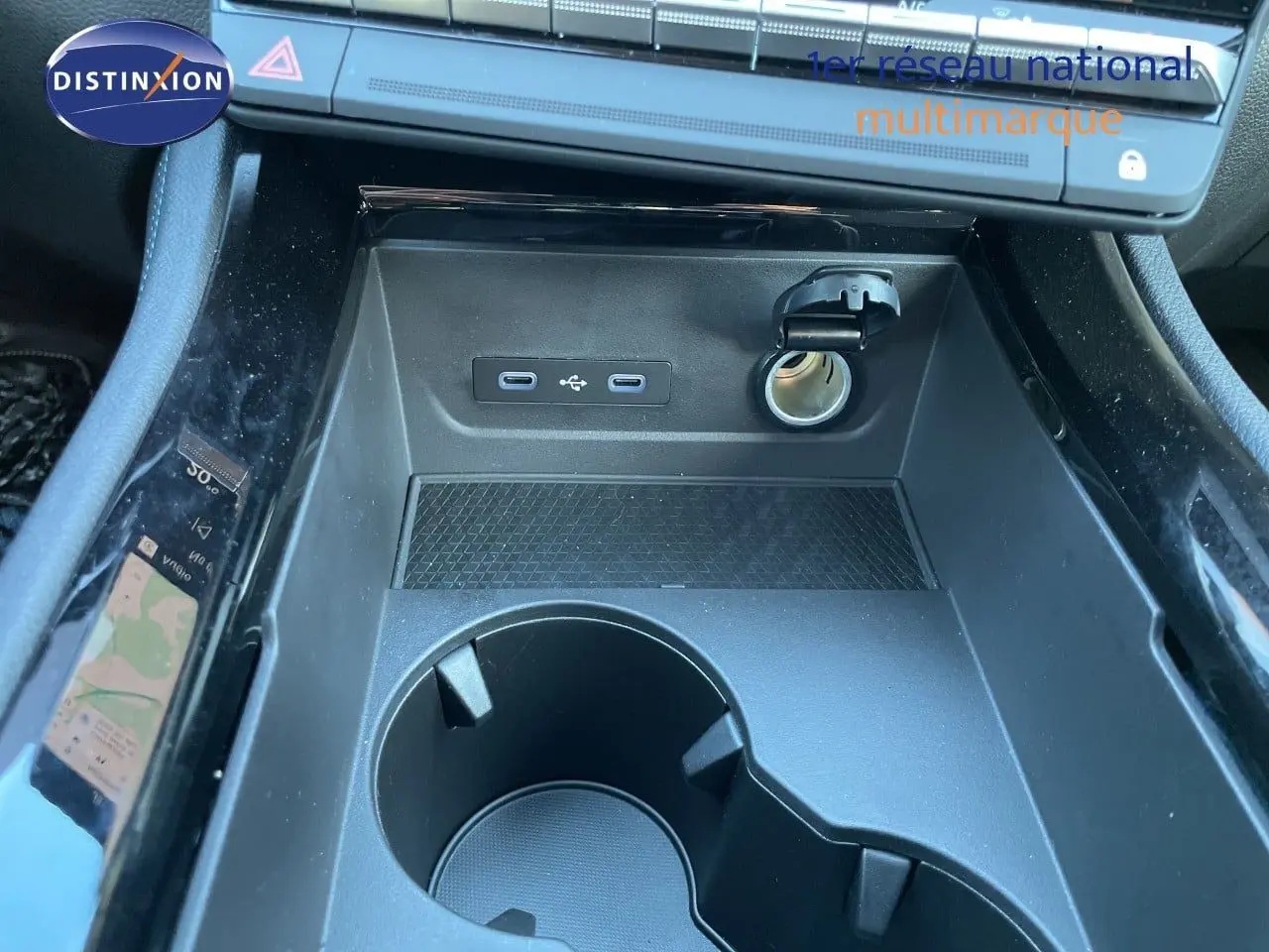 Gros plan sur la console centrale noire du Renault Austral E-Tech, montrant prises USB, allume-cigare et porte-gobelets.