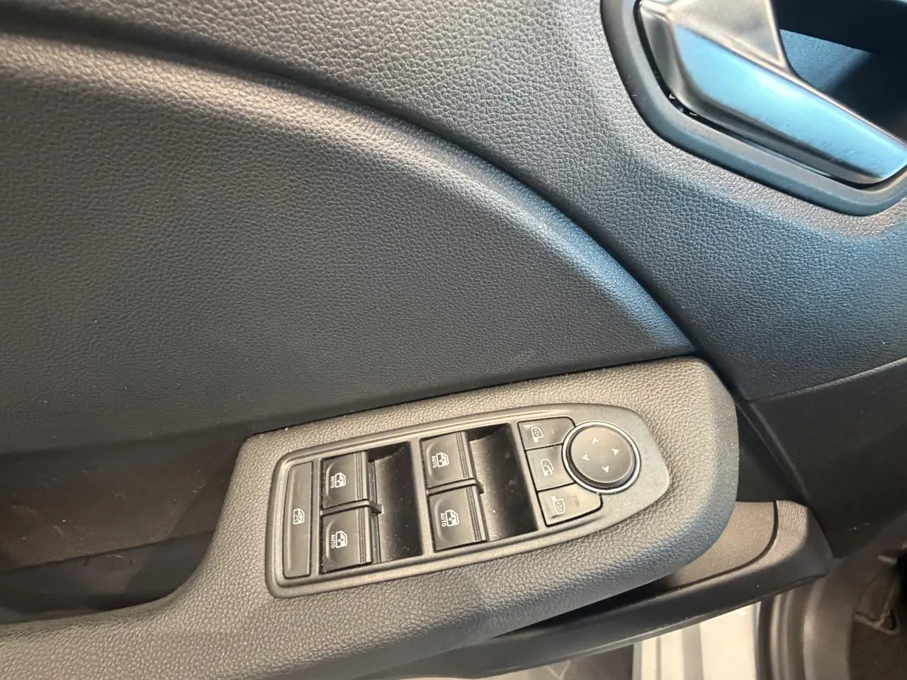 Détail des commandes de lève-vitres et rétroviseurs sur la porte côté conducteur d’une Renault Clio blanche 2024.