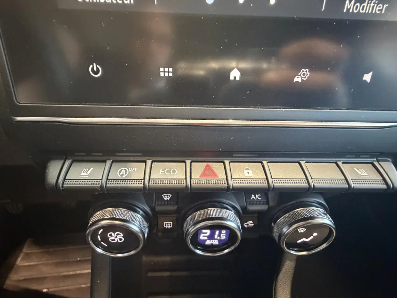 Vue rapprochée de la console centrale de la Renault Clio blanche 2024, montrant les commandes de climatisation et boutons fonctionnels.