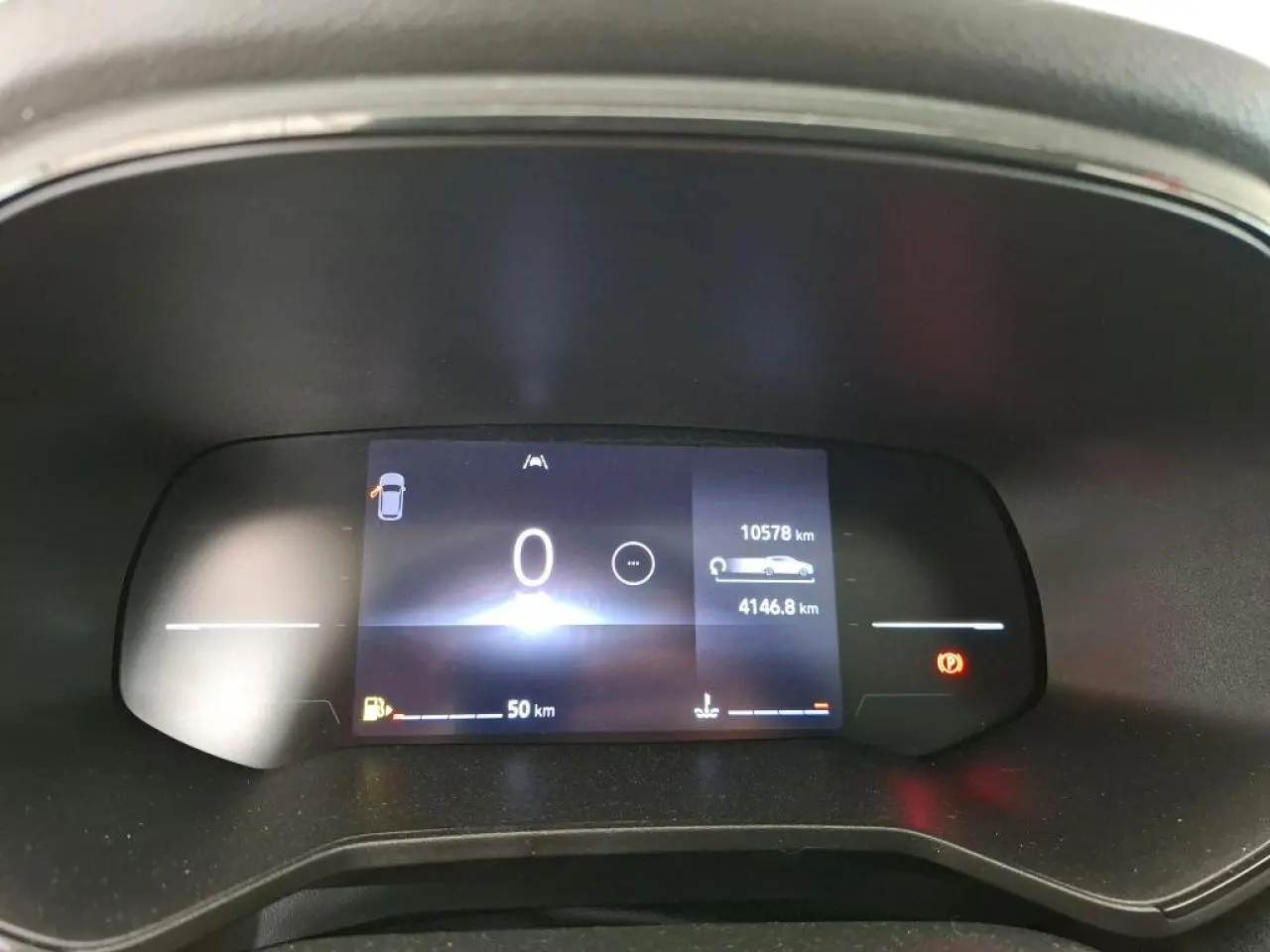 Tableau de bord numérique de Renault Clio blanc 2024 affichant compteur kilométrique et alertes au repos.