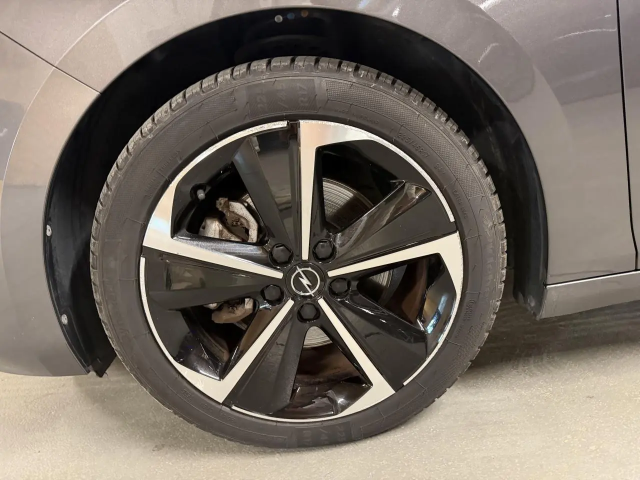 Gros plan sur la jante alliage 17 pouces diamantée noire et argentée côté gauche d’une Opel Astra gris foncé.