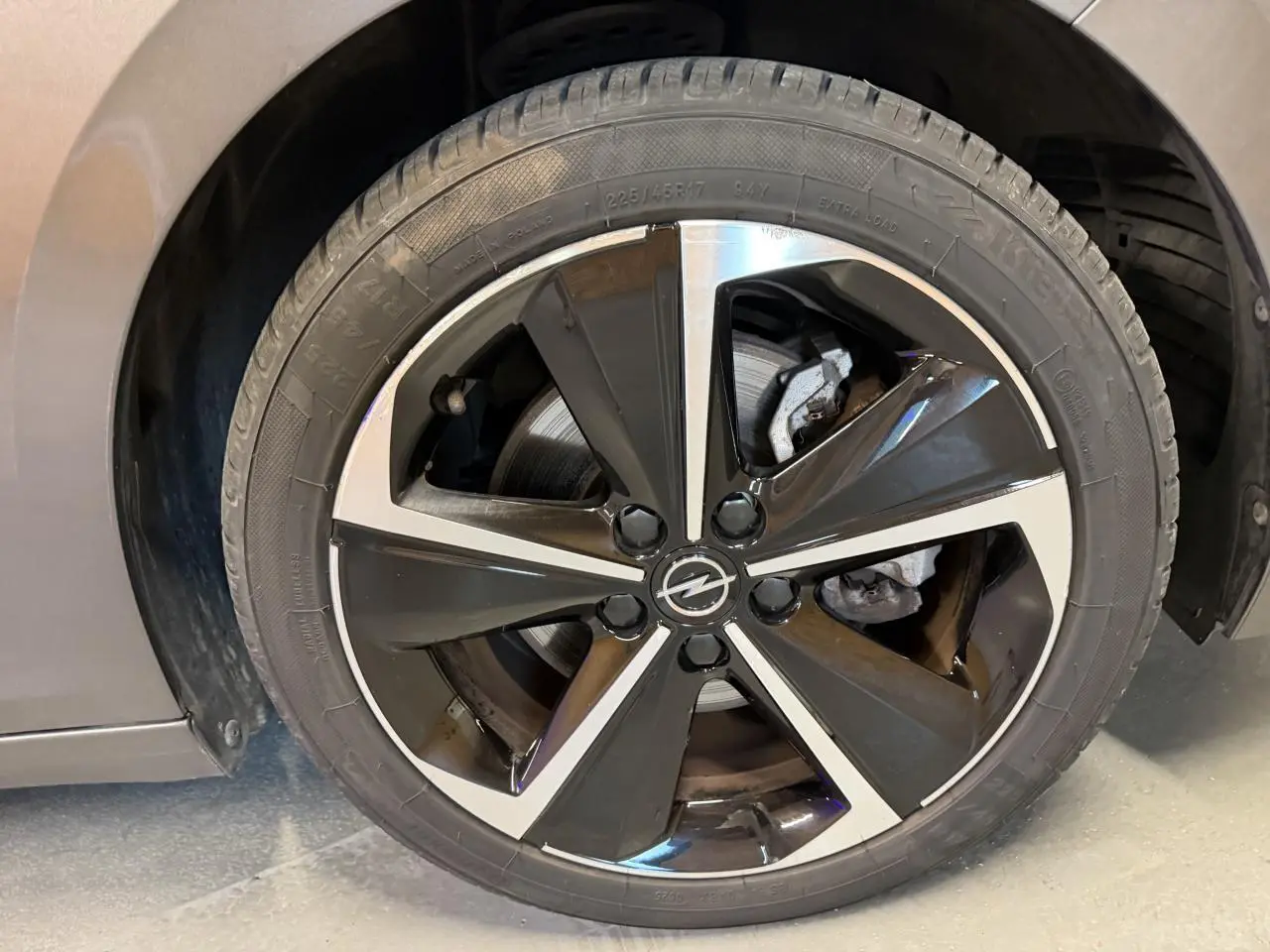 Gros plan sur la jante alliage 17 pouces noir et argent de l’Opel Astra gris foncé, avec logo Opel central.